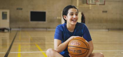 girl sitting in gymnasium with basketball