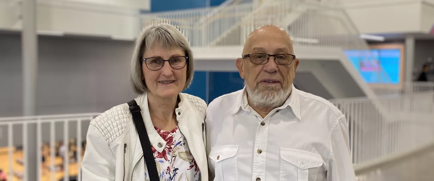 An elderly couple standing next to each other smiling