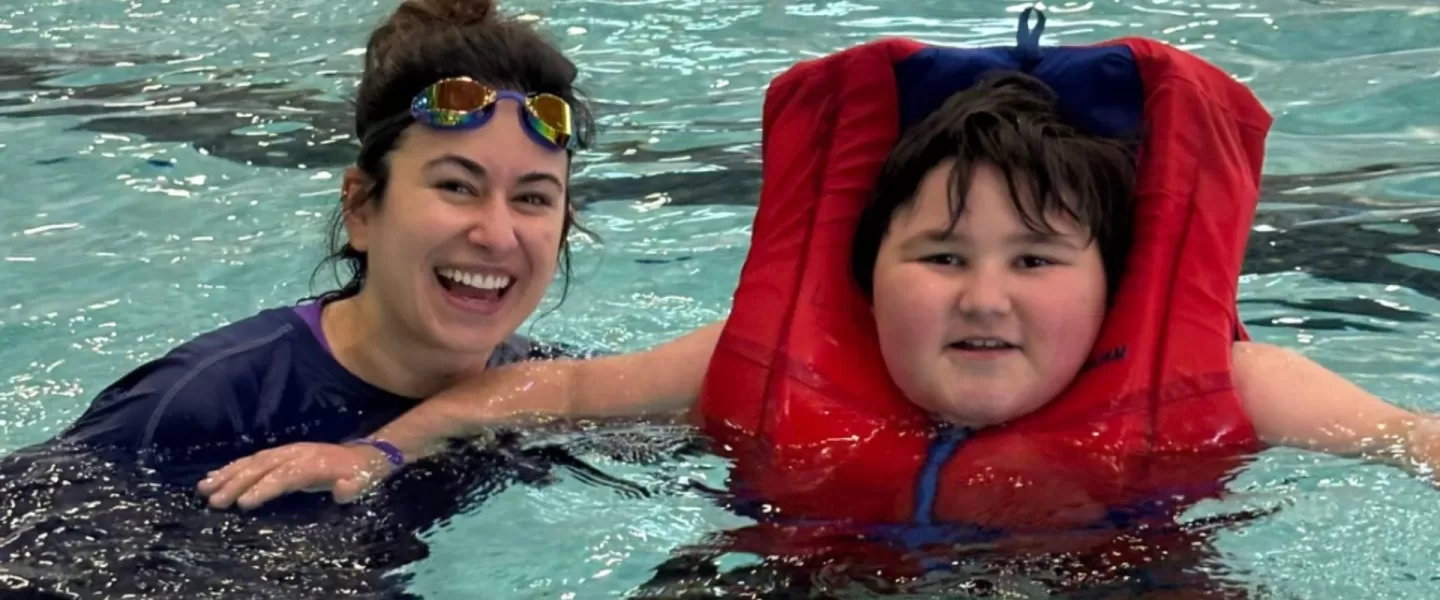 A boy and woman swimming in a pool