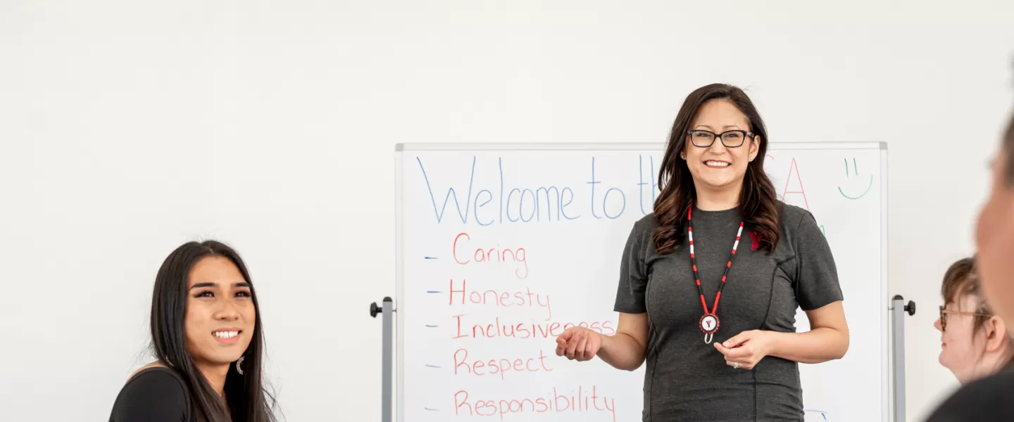 A group of people in a classroom setting, all smiling