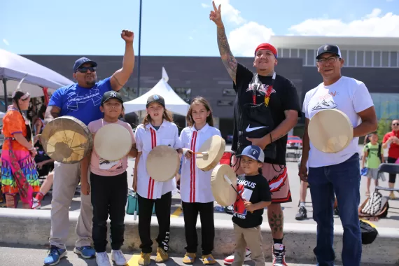 The Piikani Youth Singers pose with drums with Drezus at Brookfield Residential YMCA at Seton