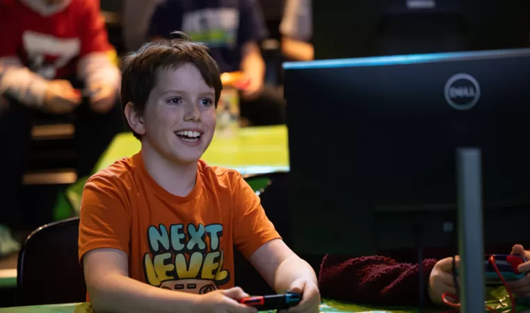 A youth smiles while playing Nintendo Switch at a YMCA esports tournament