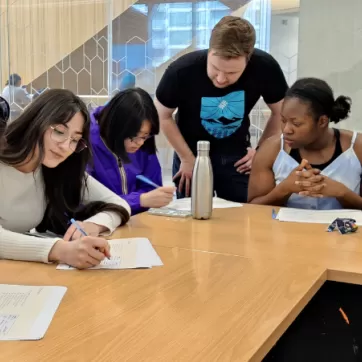 kids sitting around a table being tutored with Y logo in the top left corner