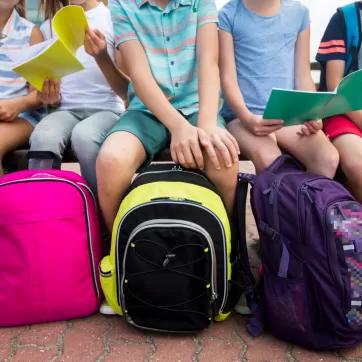 Kids sit with backpacks 