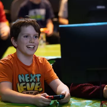 A youth smiles while playing Nintendo Switch at a YMCA esports tournament