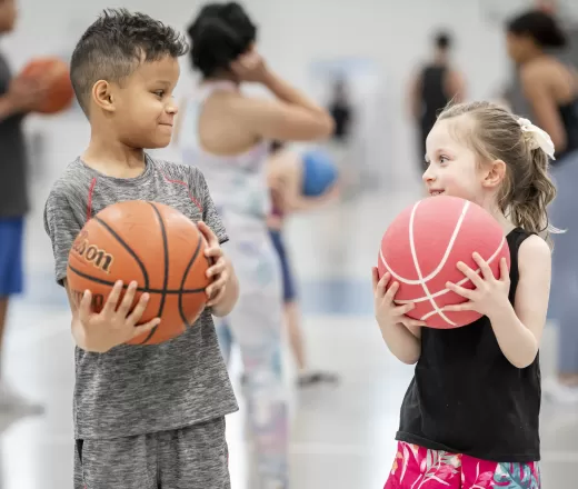 two kids holding basketballs facing each other