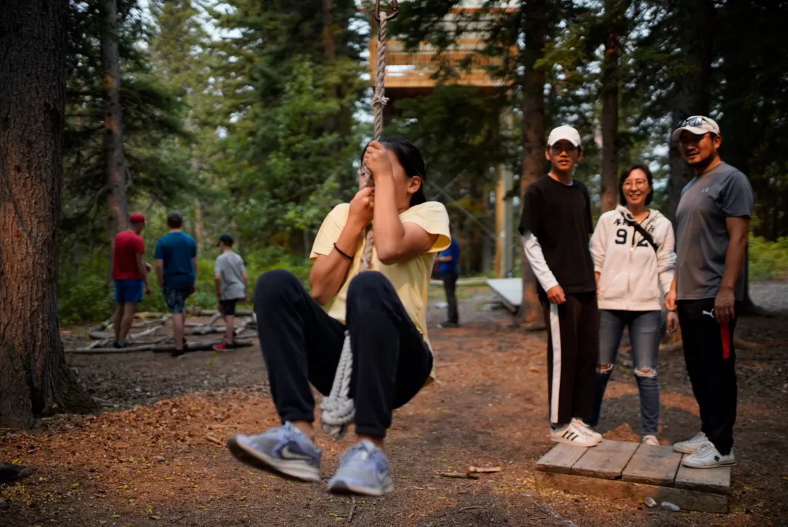 Girl on rope swing with family watching