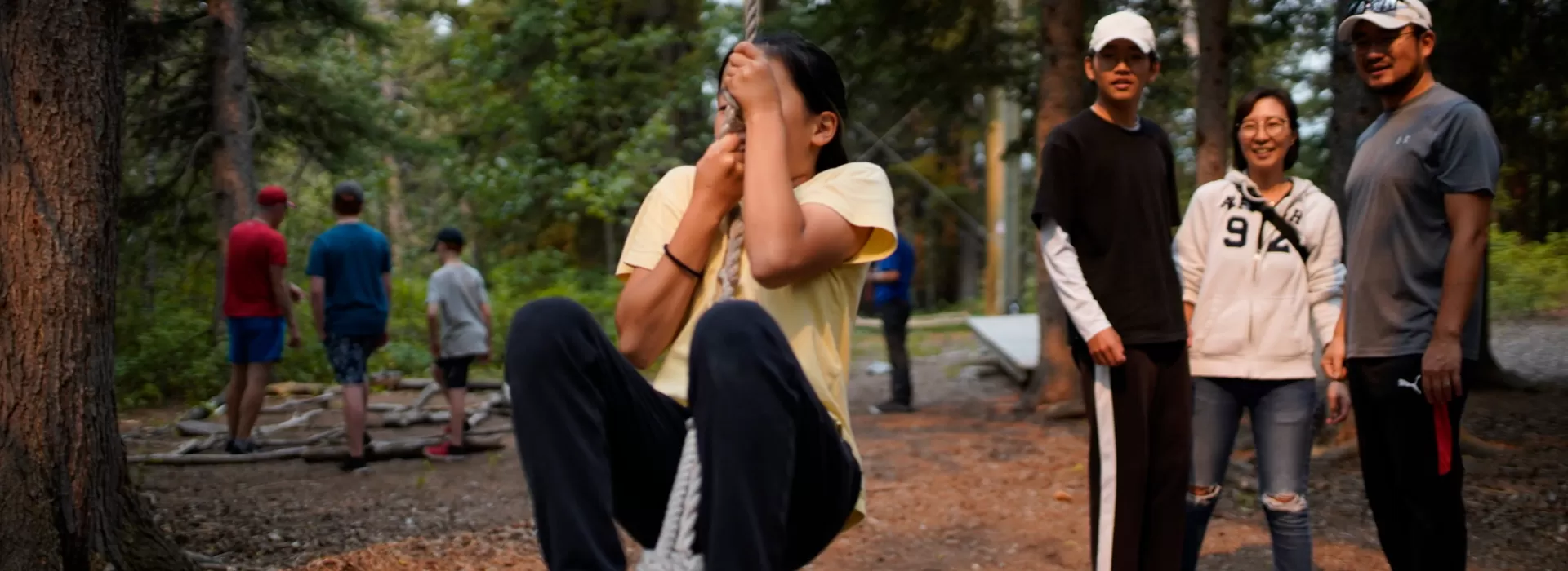 Girl on rope swing with family watching